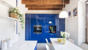 Une cuisine moderne avec des armoires bleues, un comptoir en marbre et un luminaire suspendu.
