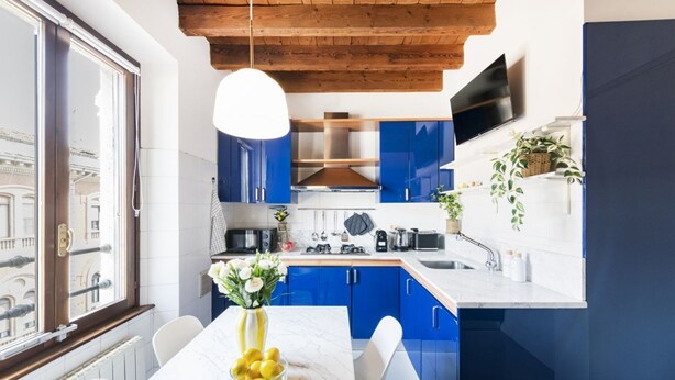 Une cuisine moderne avec des meubles bleus, un plan de travail blanc et une table en marbre.