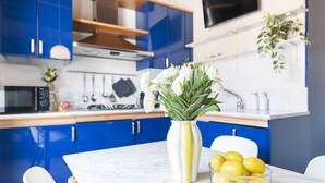 Une cuisine moderne avec des meubles bleus, un plan de travail en marbre, un vase rempli de fleurs blanches et un bol de citrons.