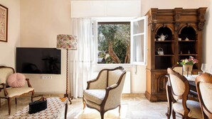 Una sala de estar con una televisión, un mueble de madera con estantes y una ventana que ofrece vistas a árboles.