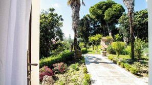 Un sentier de jardin mène à un petit bâtiment, qui est entouré de différents arbres et arbustes.