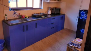 A compact kitchen with a sink, stove, microwave, and cabinets. - Charming 1-bedroom apartment with WiFi, AC in vibrant Goa (Goa)