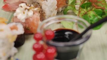 A plate of sushi with various toppings and a small bowl of soy sauce.