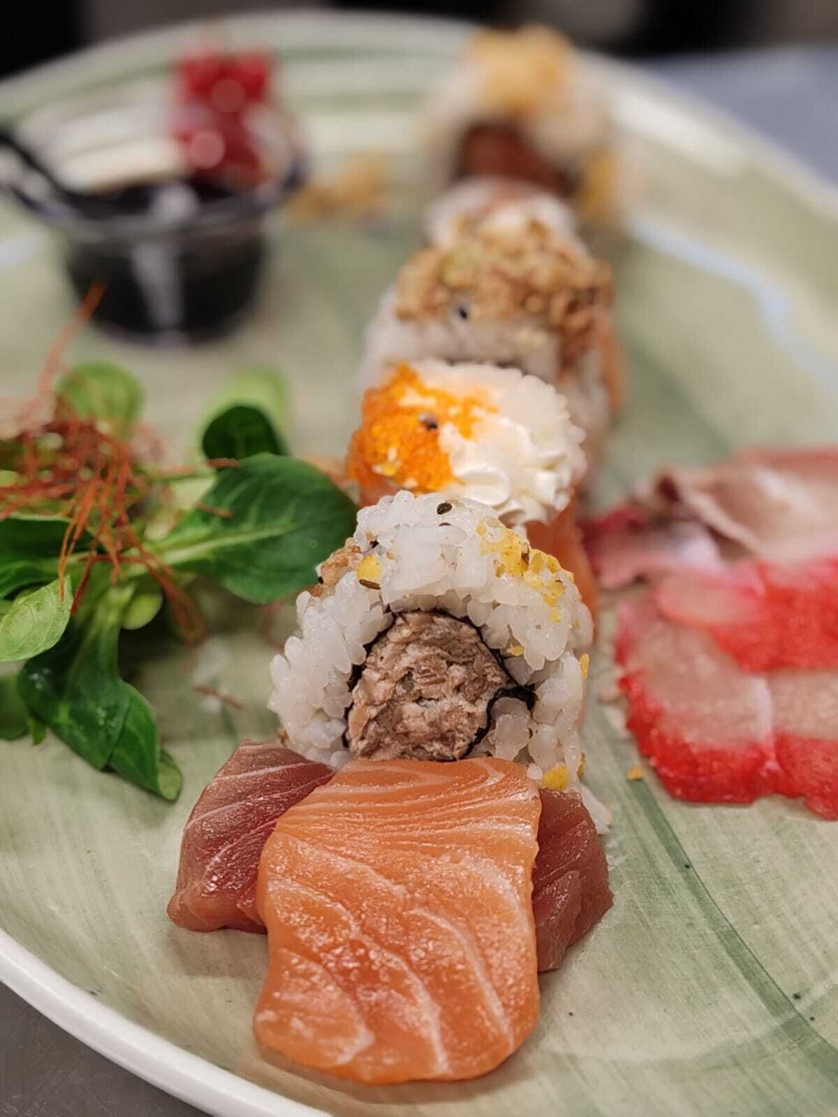 A plate with sushi rolls and sashimi.