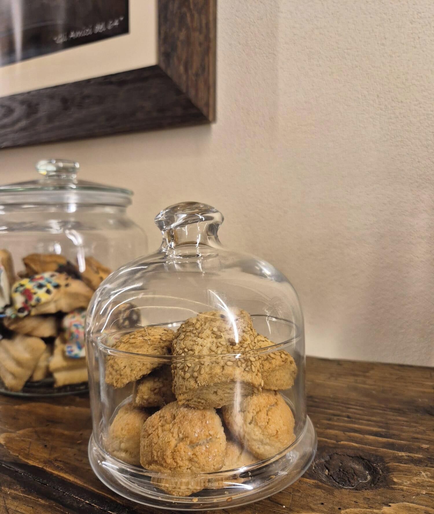 A glass jar with a lid containing cookies on a wooden surface.