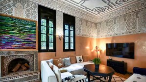 Uma sala de estar com sofá, lareira, paredes estampadas e televisão.