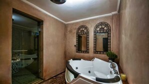 Casa de banho com uma banheira grande, dois espelhos elaborados e cabine de duche em vidro.