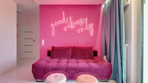 A bedroom with a pink wall, a bed, and two glass-topped side tables. - Żurawie Pink Port by Grand Apartments (Gdańsk)