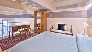 A bedroom with a large bed, a wooden desk, a chair, a sofa, a mirror, and a nightstand with a lamp. - Venus apartment (Firenze)