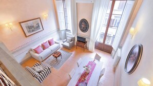 A spacious living area with a white sofa, striped armchair, and a dining table set with a vase of flowers. - Venus apartment (Firenze)