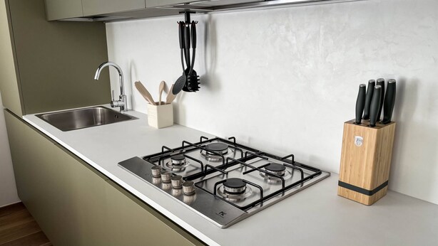 A kitchen with a stainless steel gas stove, a sink, and a knife block.