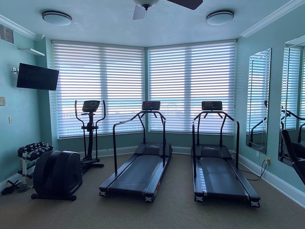 Un gimnasio con cintas de correr, una bicicleta estática y mancuernas.