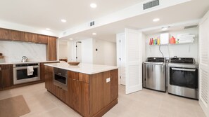 A modern kitchen with wooden cabinetry, stainless steel appliances, and a central island.