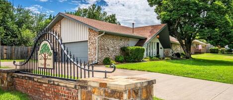 A residential house with a stone facade, a garage, and a well-maintained lawn.