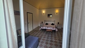 Une chambre à coucher comprenant un lit, des tables de chevet, un banc, une porte et un revêtement de sol à motifs.