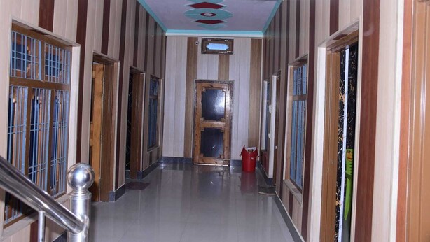 Um corredor com paredes listradas, piso ladrilhado e uma porta central.