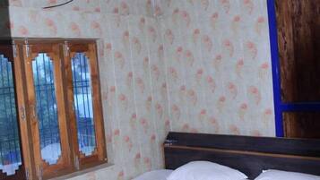 A bedroom with a bed, an air conditioner, a ceiling fan, and a window with a wooden frame.