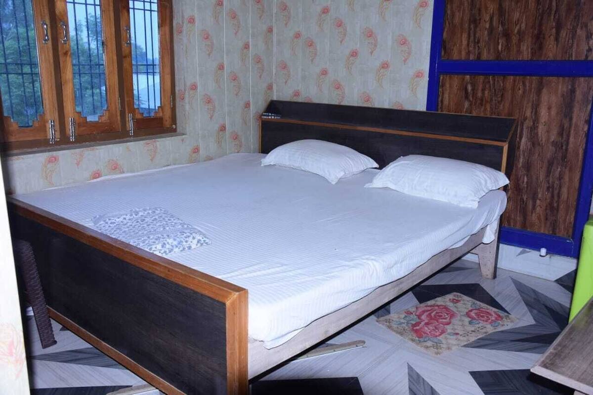 A single bed with a wooden frame and white bedding in a room with patterned wallpaper and a geometric floor design.
