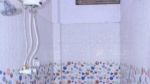 Um banheiro pequeno revestido com azulejos, com vaso sanitário, aquecedor de água e janela.