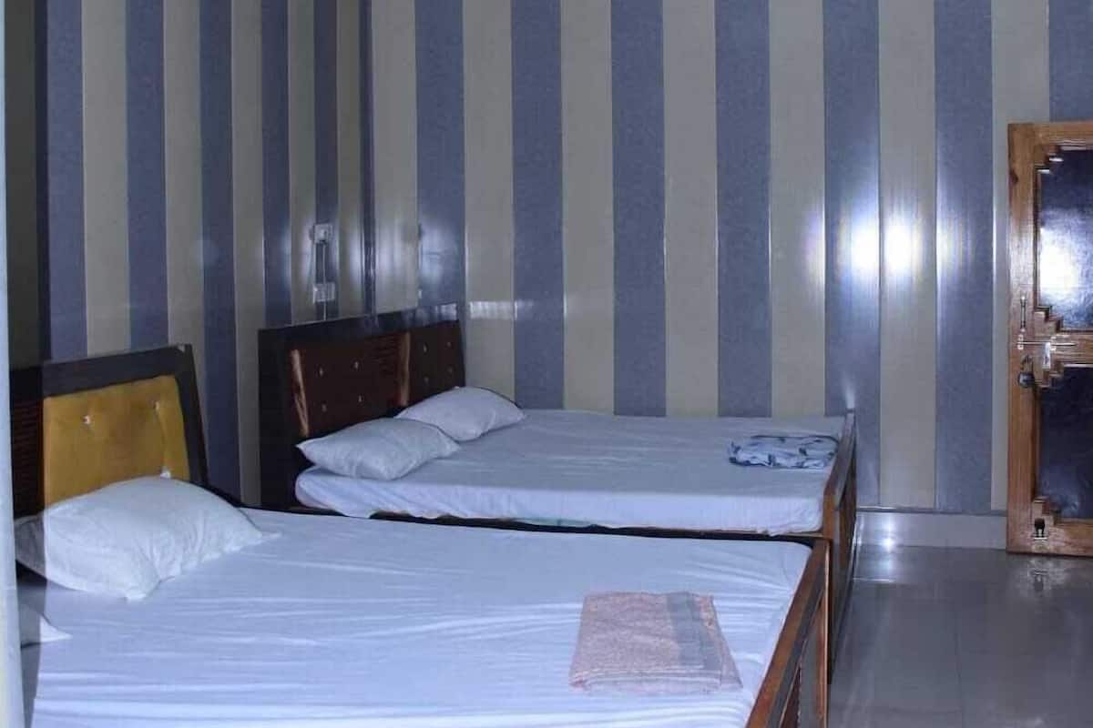 A hotel room with two beds, striped wallpaper, a ceiling fan, and a wooden door.