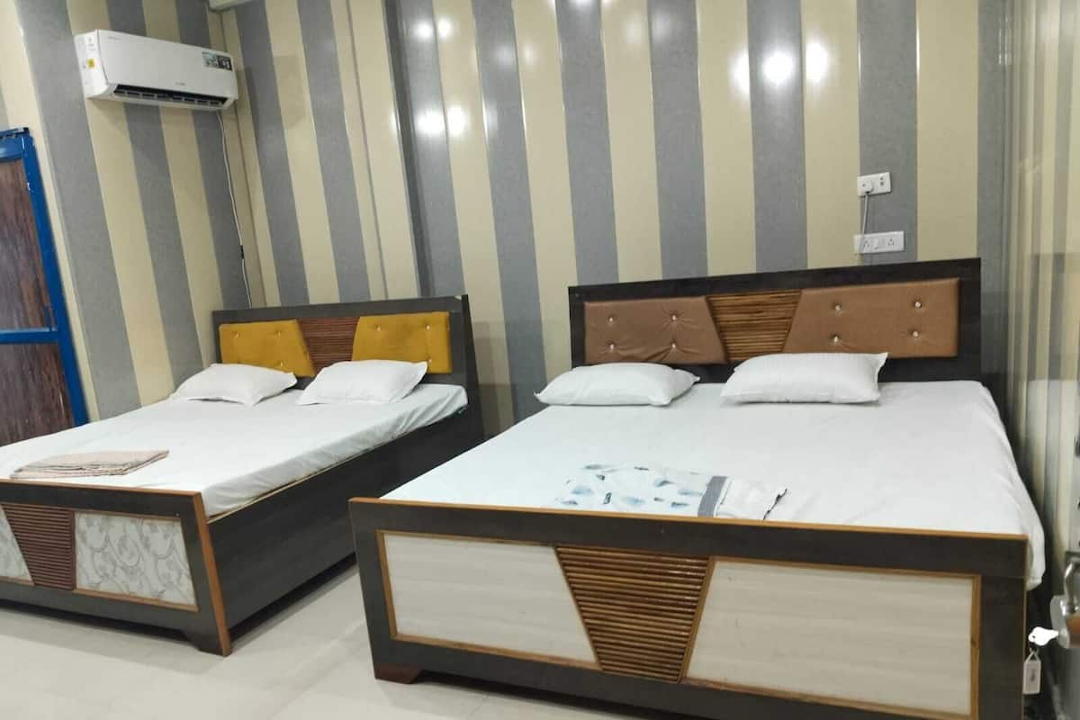 Two single beds with wooden frames and headboards, a striped wall, and an air conditioning unit above the beds.