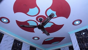 Teto com um ventilador e um desenho abstrato em vermelho e azul.