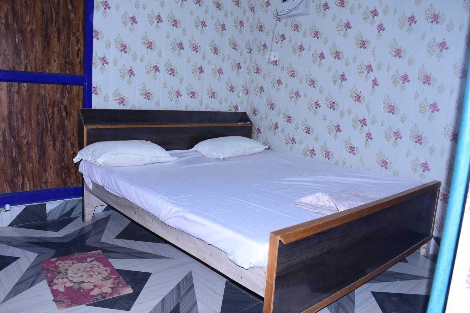 Un letto singolo con biancheria da letto bianca in una stanza con carta da parati floreale e pavimento a motivi geometrici.