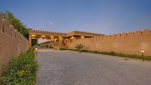 A courtyard with a paved walkway, a covered entrance, and decorative wall patterns. - Hariyali Dhani Camps & Desert Resort With Swimming Pool, Jodhpur (Dheerpura)