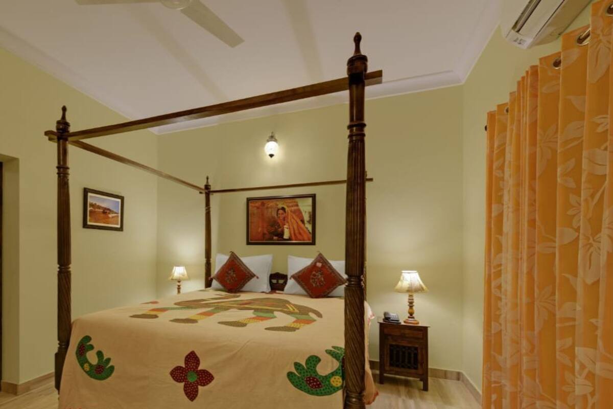 Una cama con dosel, un edredón con motivos florales, dos lámparas de noche y una mesita de noche con lámpara.