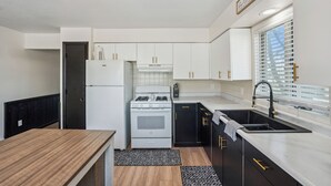 A modern kitchen with white cabinets, a black countertop, and a stainless steel sink. - The Big Muddy Riverfront Bungalow (Princeton)
