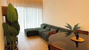 Ein modernes Wohnzimmer mit einer Eckcouch, einem Esstisch und einer großen Kühlpflanze.