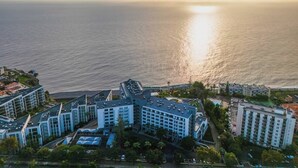 Ein Hotelkomplex an der Küste mit mehreren Gebäuden, einem Parkplatz und Blick aufs Meer.