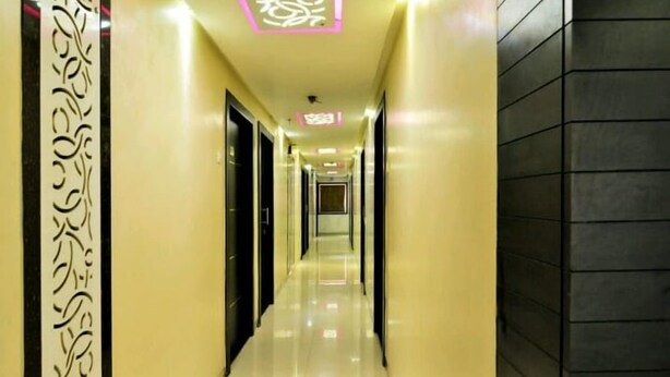 Un pasillo con suelo de baldosas brillantes, puertas negras y un panel decorativo en la pared izquierda.