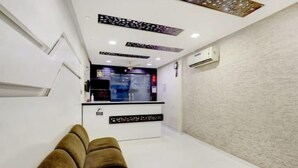 Un moderno vestíbulo de hotel con mostrador de recepción, zona de estar y paneles decorativos en el techo.
