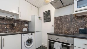 Una cucina moderna con mobili bianchi, una lavatrice, un forno e una lavagna con ricette.