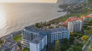 A coastal cityscape with modern buildings, a bridge, and a beach. - To complete (Funchal)