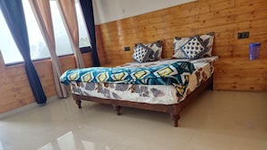Een kamer met houten lambrisering, een bed, gordijnen en een betegelde vloer.