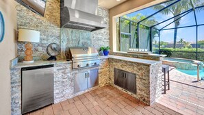 Una cocina moderna con una parrilla incorporada, lavavajillas y vistas a una piscina.