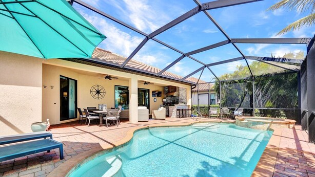Una piscina con un porche cubierto, mobiliario exterior y una pared decorativa.