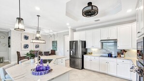 Una cocina moderna con armarios blancos, electrodomésticos de acero inoxidable y encimera de mármol.