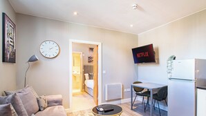 Una sala de estar moderna con un sofá, una mesa de centro y un televisor mostrando 'NETFLIX'.