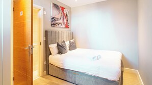 Un dormitorio con cama, una puerta de madera y un cuadro en la pared.