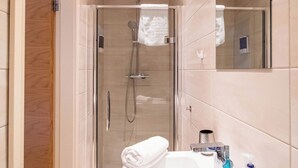 Un baño moderno con ducha, lavabo con espejo y barra para toallas.