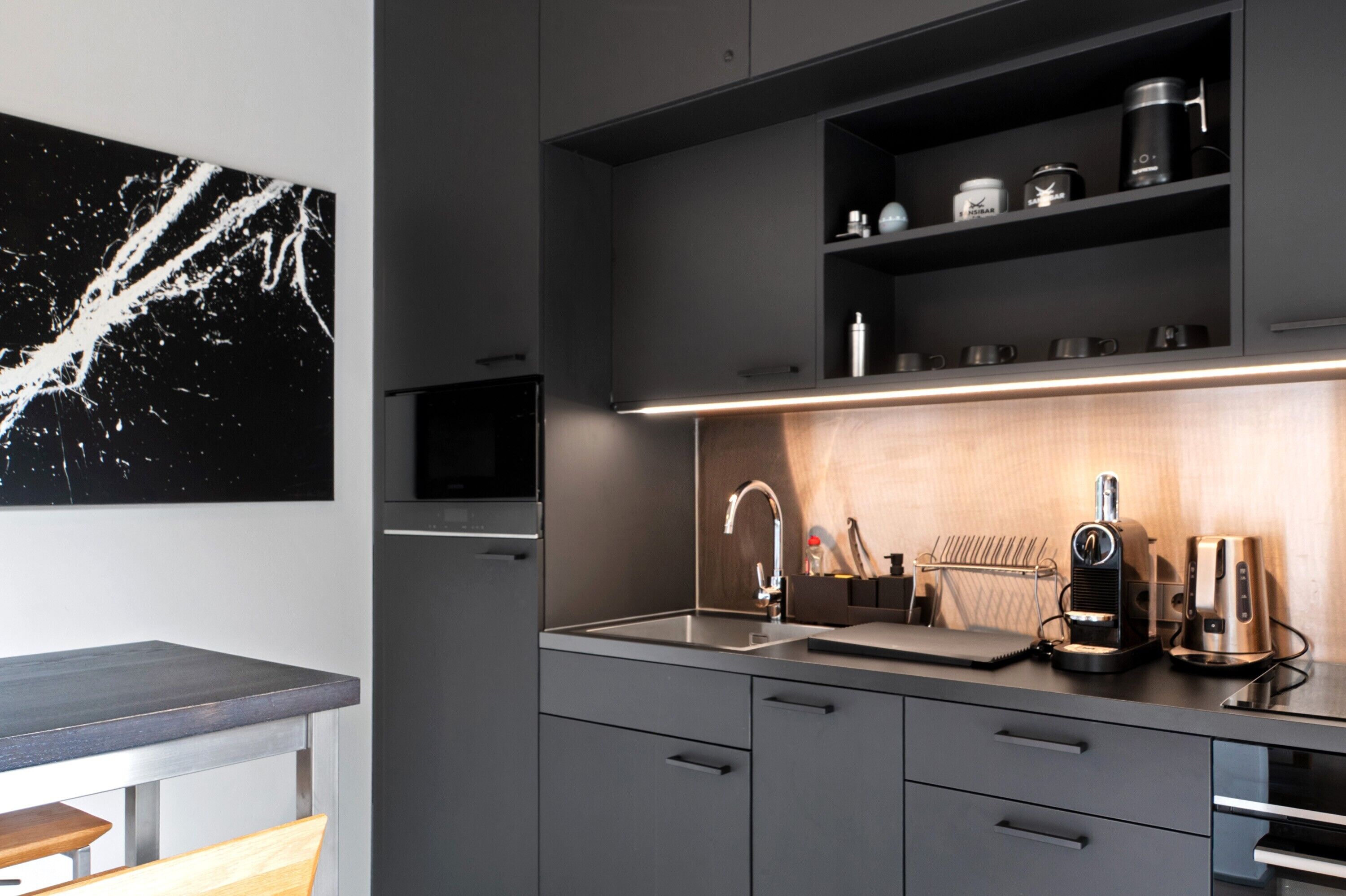 Una cucina moderna con forno a incasso, microonde e macchina del caffè sul piano di lavoro.