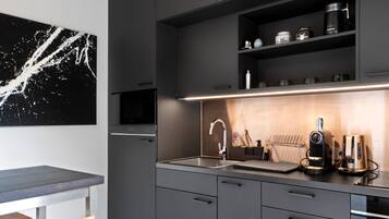 Una cucina moderna con forno a incasso, microonde e macchina del caffè sul piano di lavoro.