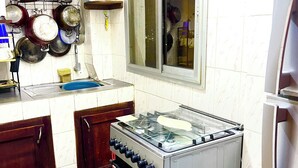 A kitchen with a stainless steel stove, wooden cabinets, a window, and a tiled backsplash.