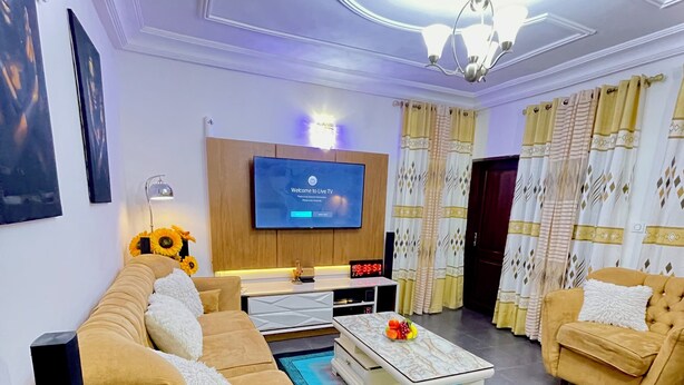 A modern living room with a sofa set, a coffee table, and a flat-screen TV mounted on the wall.