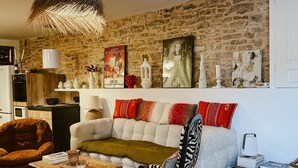 Una sala de estar acogedora con pared de piedra, un sofá, un sillón estampado con motivos de cebra, una mesa de centro y una lámpara colgante.