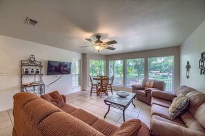 A living room with a ceiling fan, a TV, a dining table with chairs, and two sofas.