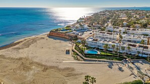 A coastal resort with beachfront villas, a swimming pool, and a sandy beach.